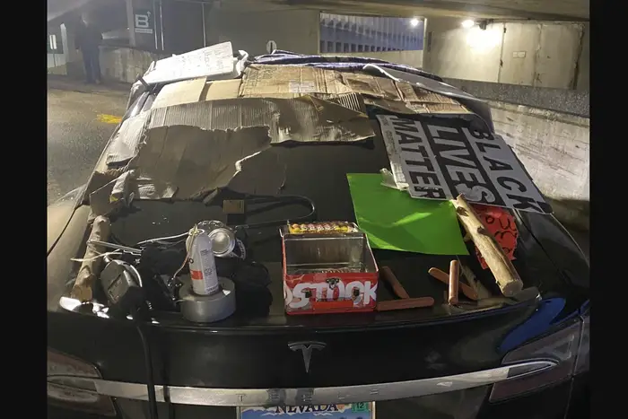 A photo of a Tesla with aerosol cans, a Black Lives Matter sign, hot dogs, and other miscellany